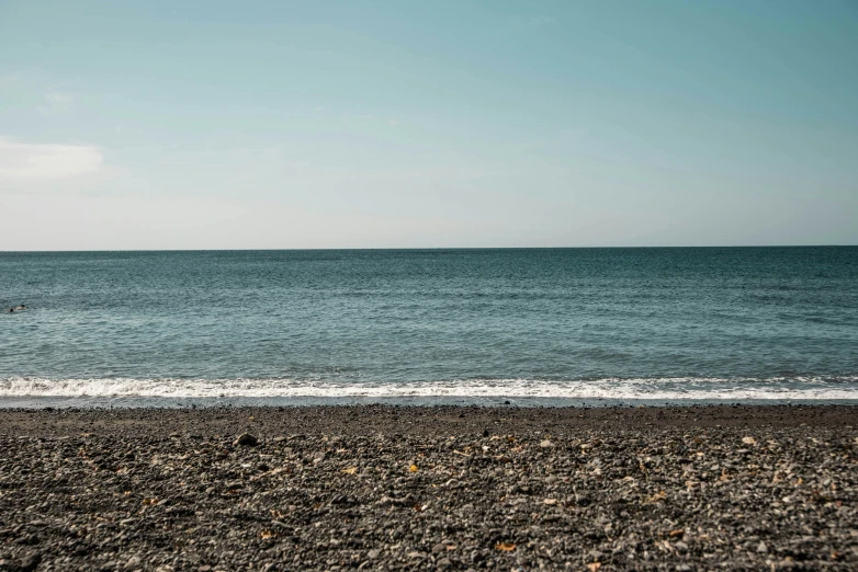 a small boat in the distance with an ocean and sky