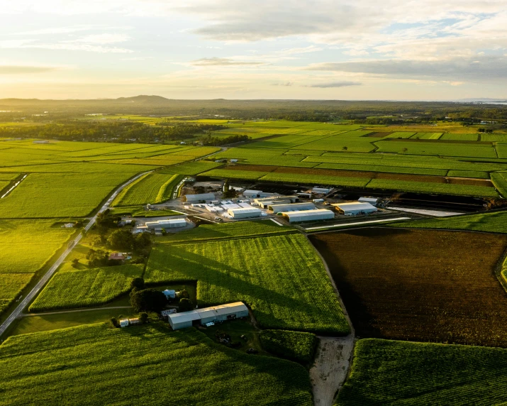 an aerial po of a farm with large green fields in the background