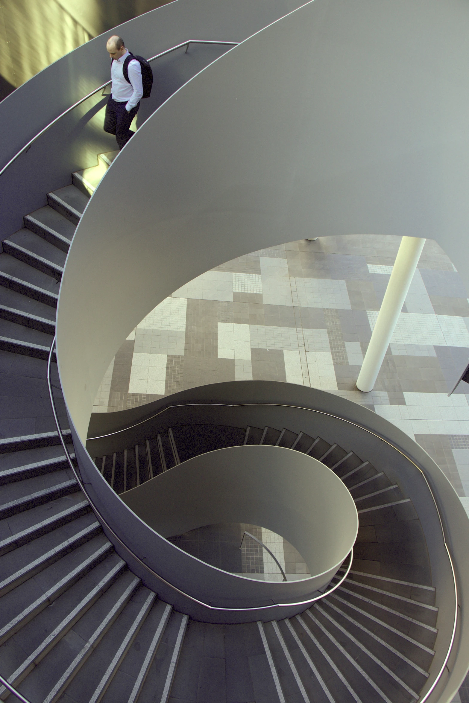 a spiral staircase inside a building with people walking around