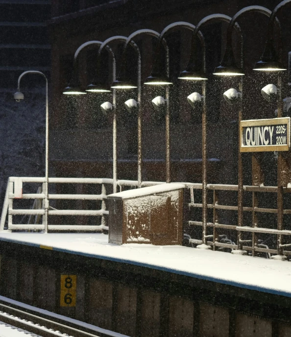 a train track with a sign and lights covered in snow