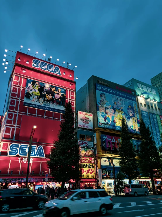 there are cars driving along the street in front of an illuminated building