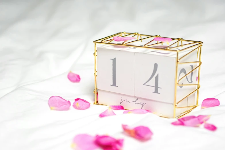 a gold and white calendar sitting on top of a bed of rose petals