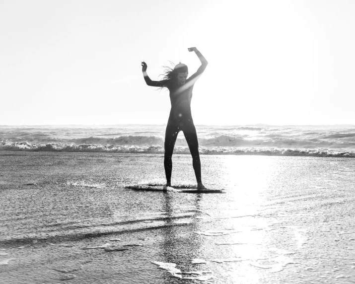 a surfer is standing in the water waving to the sky