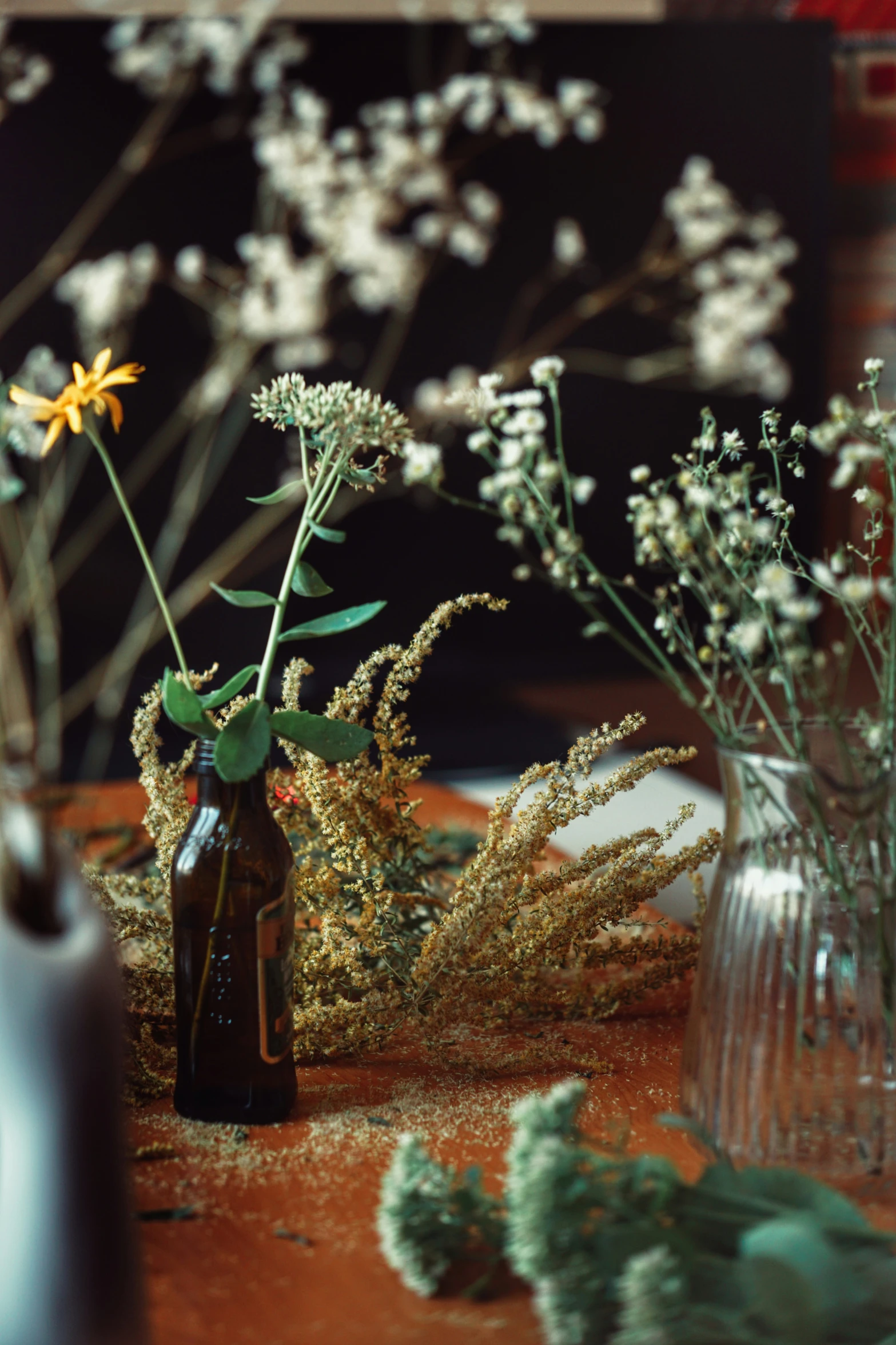 a table with vases, a bottle and some white flowers