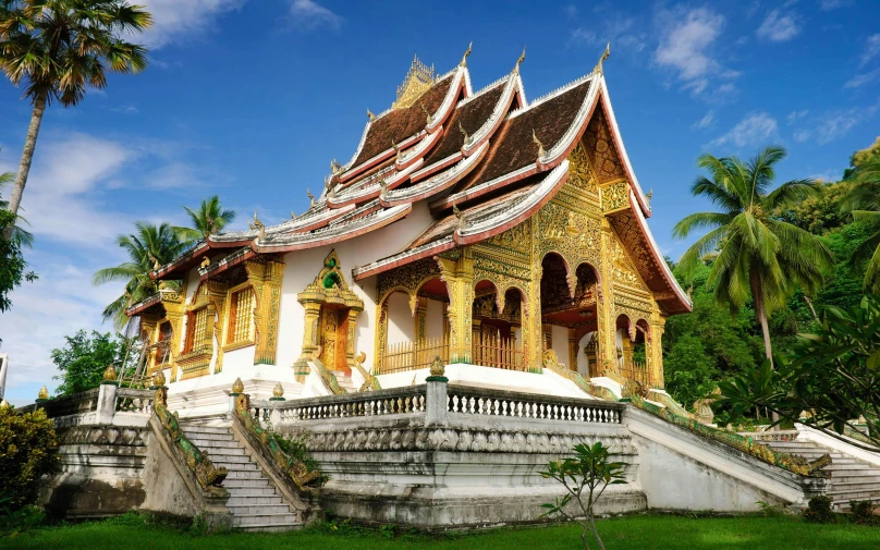 an elaborate golden and white building in the middle of a park