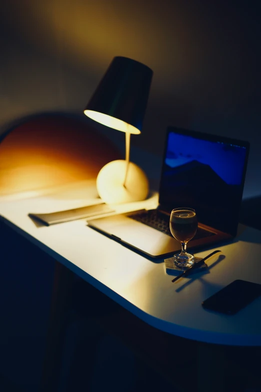 the computer on the small table has a drink in front