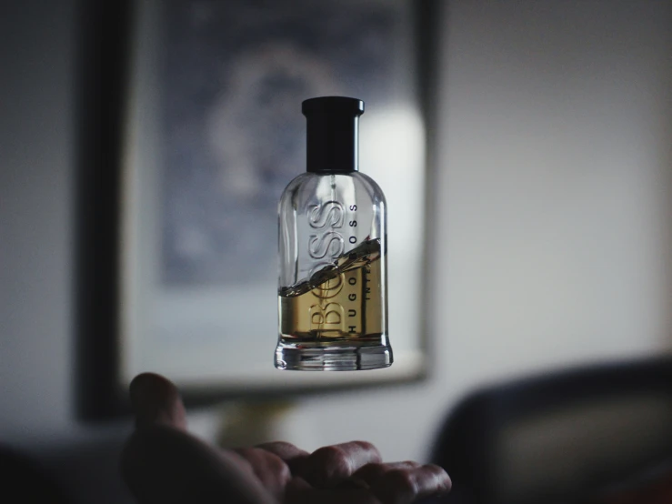 a hand holding up an empty bottle with a design inside