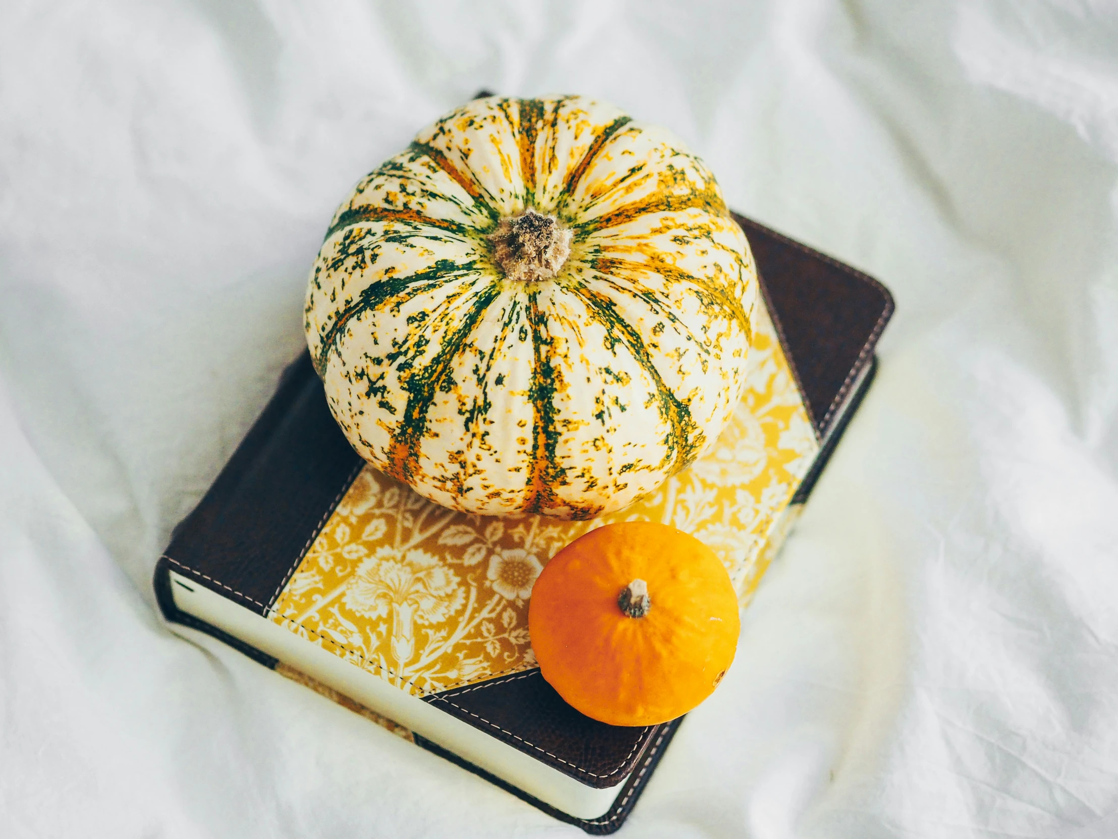 pumpkins sitting on top of a book in front of white sheets