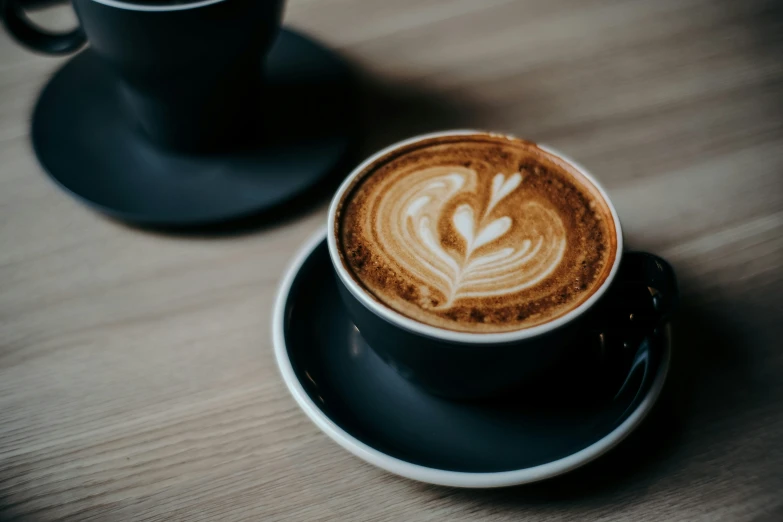 a latte cup and saucer with white art design