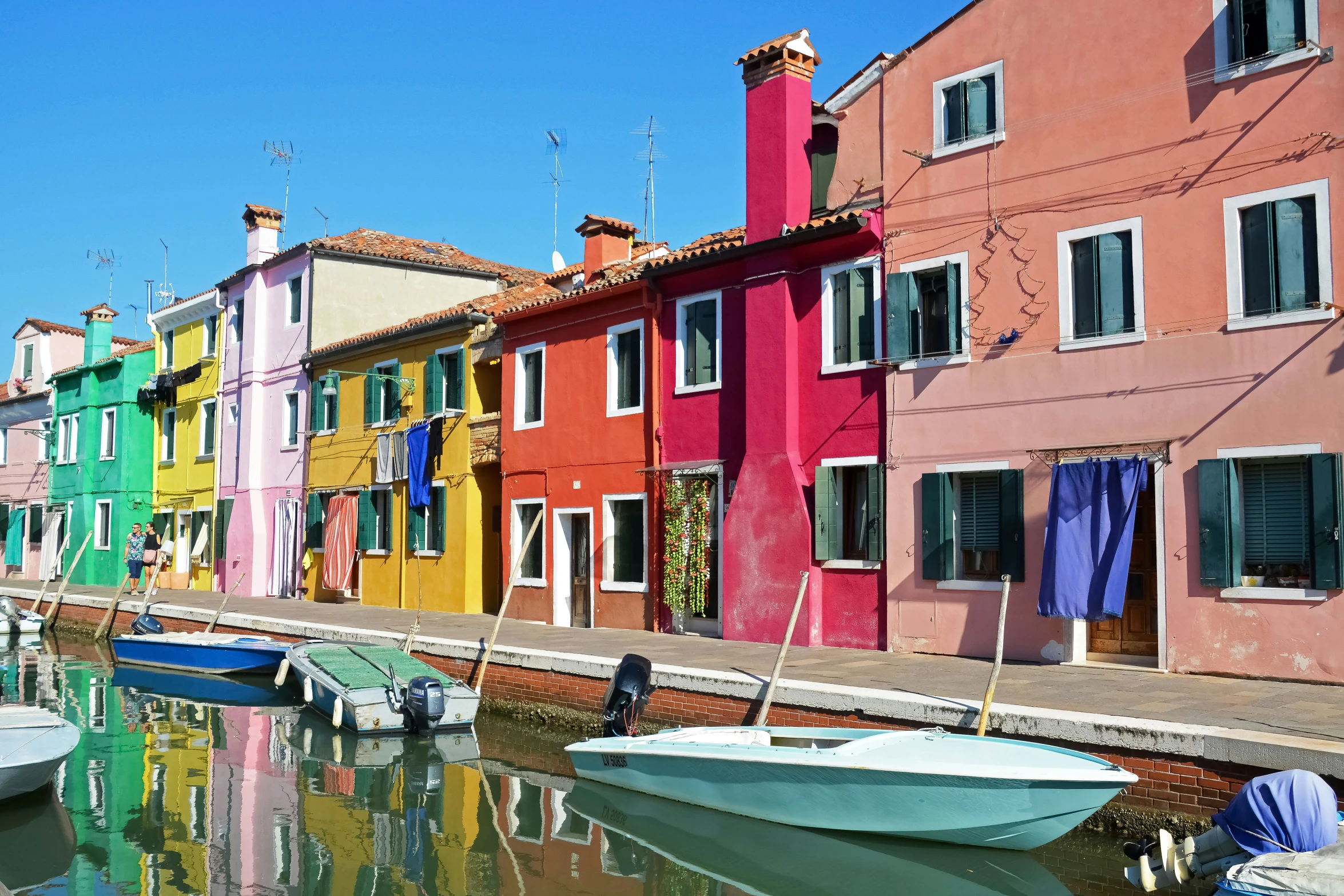 a canal runs through a row of houses with boats in front