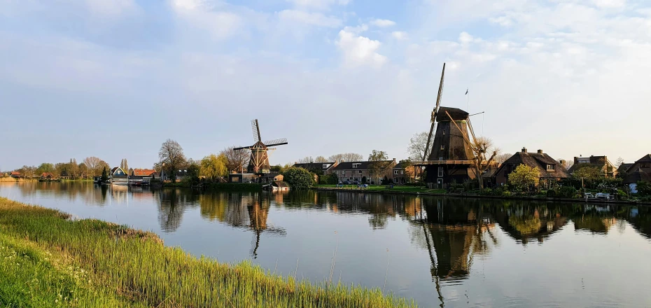 a windmill and houses on the side of a river