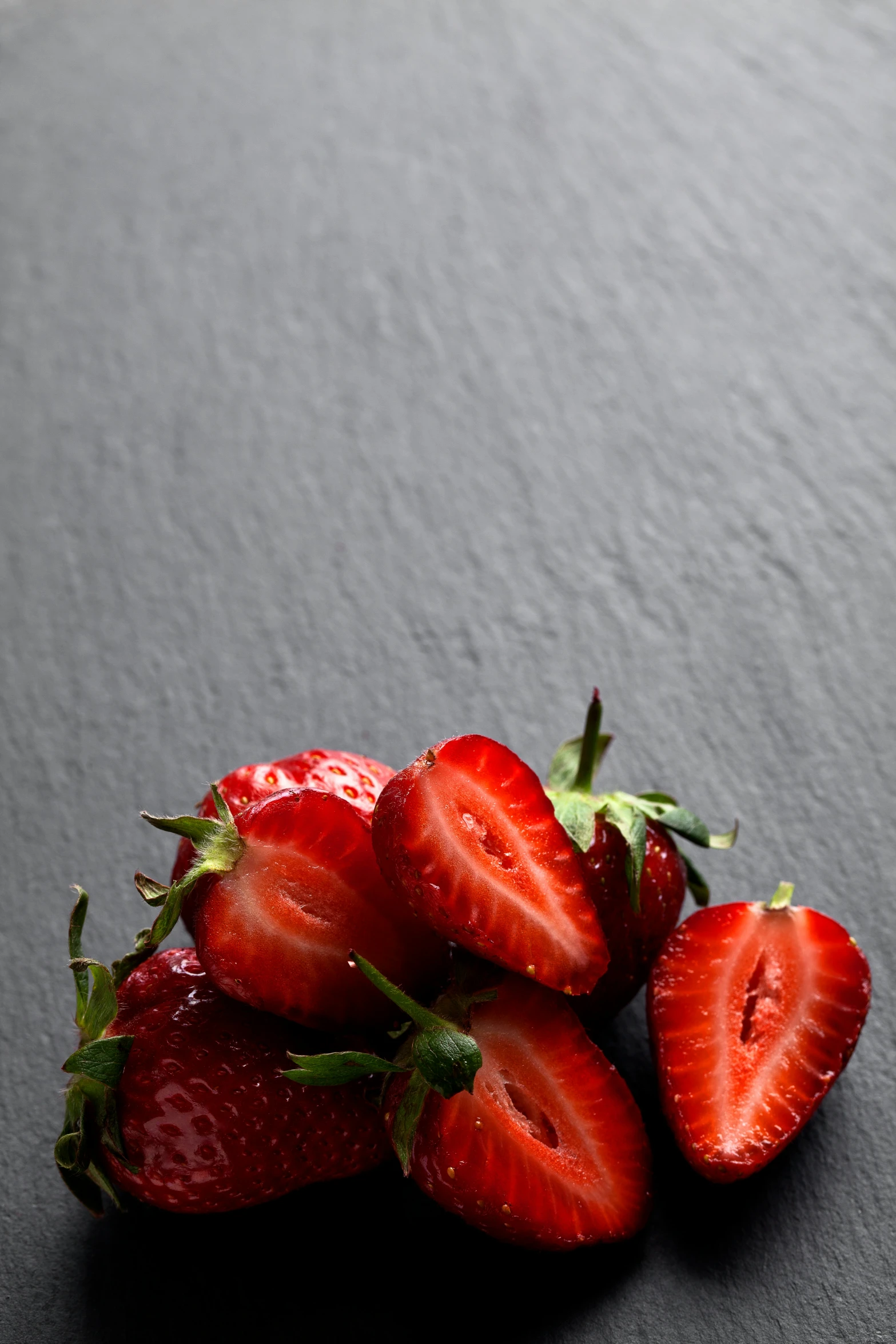 some strawberries lay on a table with their tops exposed