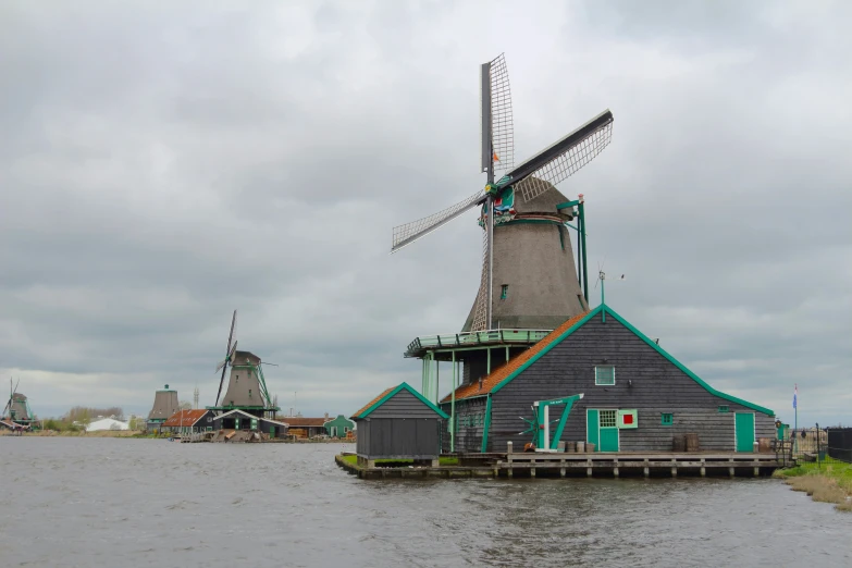 there is a windmill on the water near the house