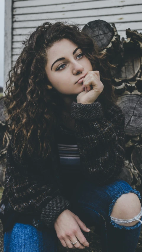 a woman sitting on the ground with her hand resting her chin