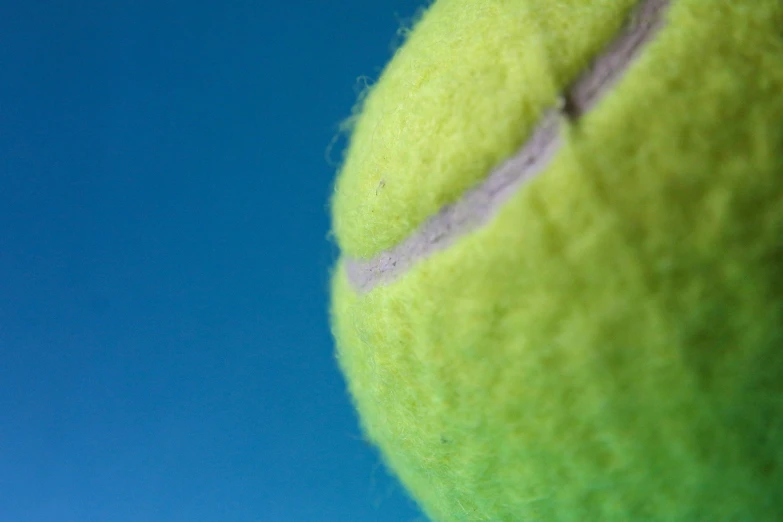 an extreme closeup of the top half of a green tennis ball