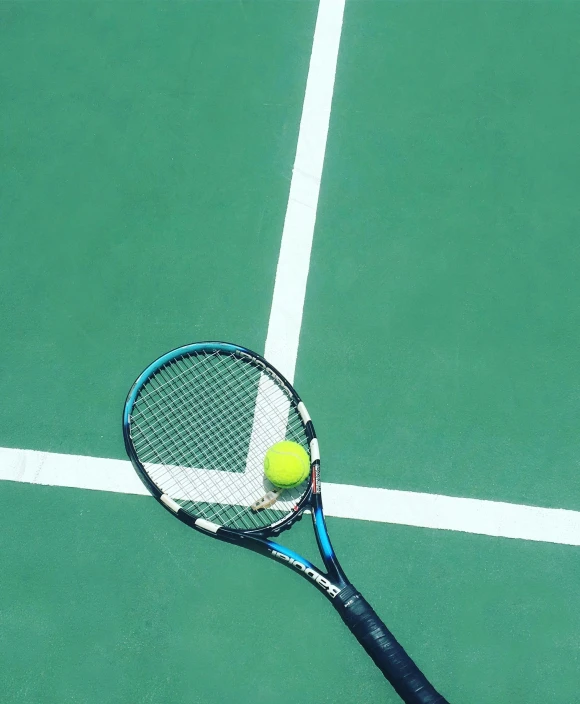 a tennis racket is on the ground and a yellow ball is in the air