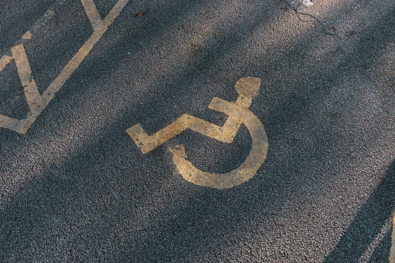 a handicap sign is on the road that appears to be worn down