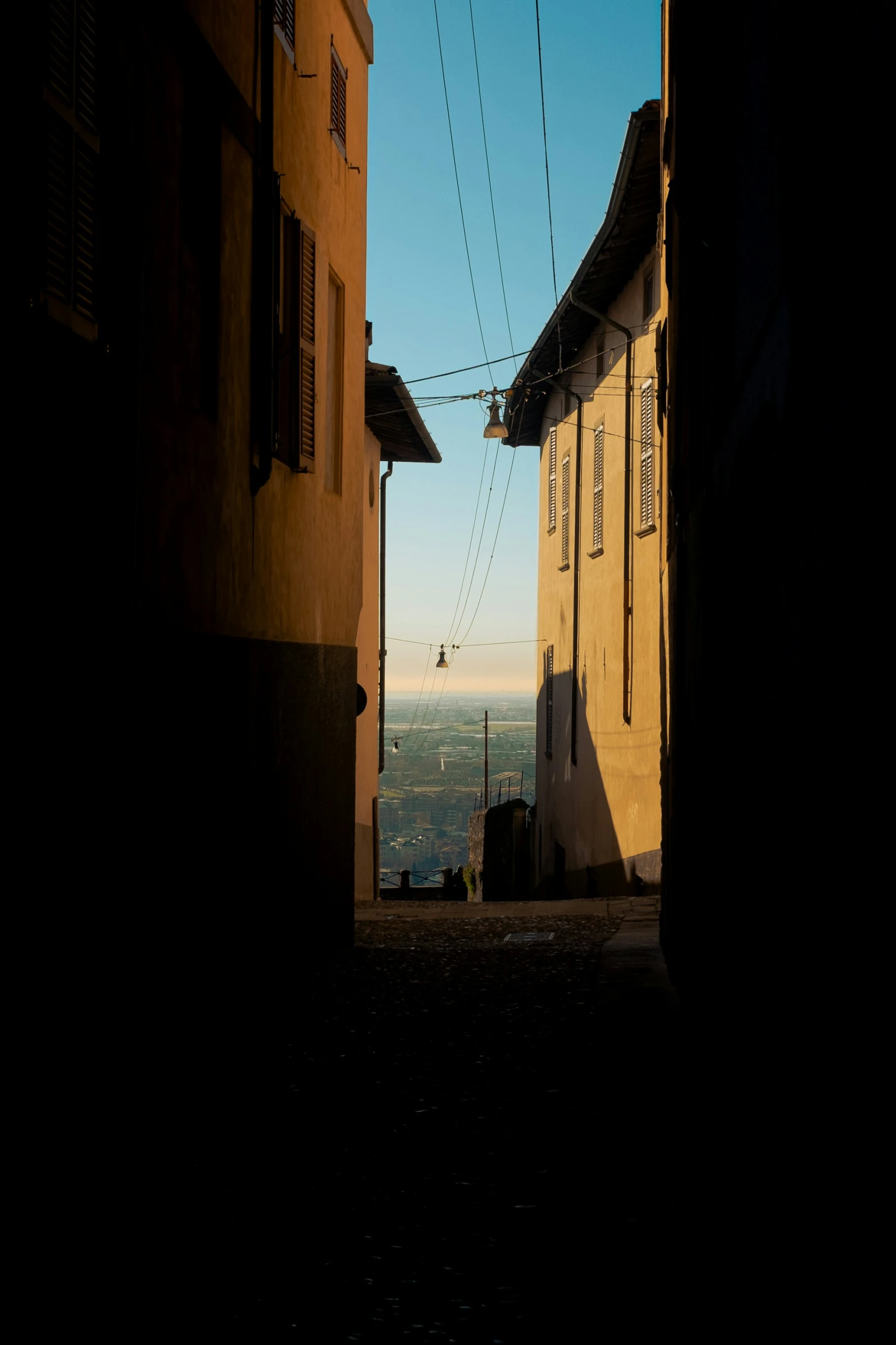 an alley way between two buildings with electrical wires over them