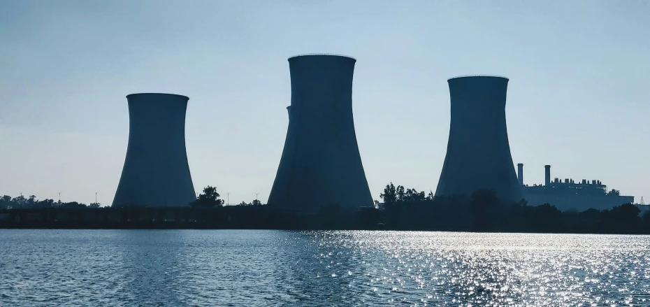 three cooling towers are silhouetted against the blue sky