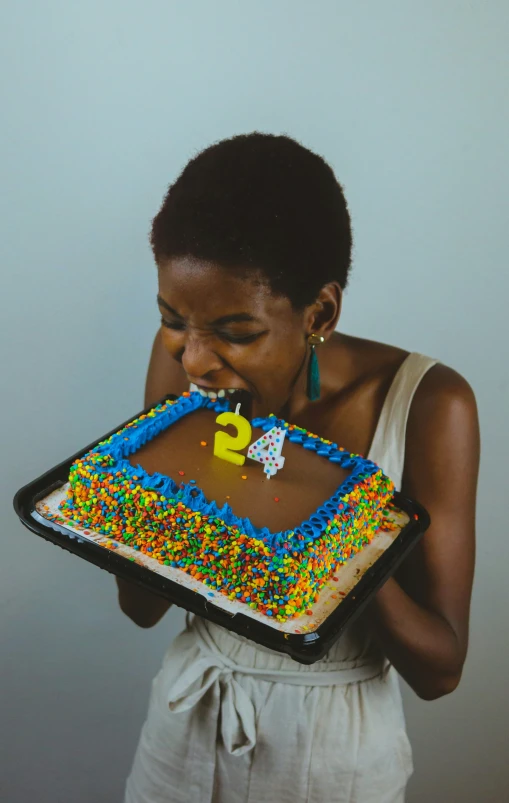 woman holding a large cake with icing and rainbow sprinkles