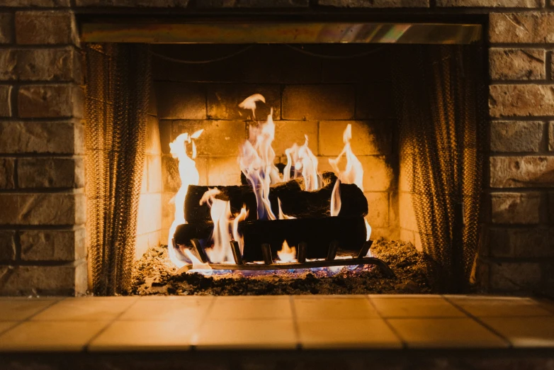 a fireplace with fire burning in it and a rug on the floor below