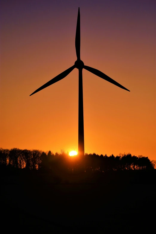 a wind turbine silhouetted by the setting sun