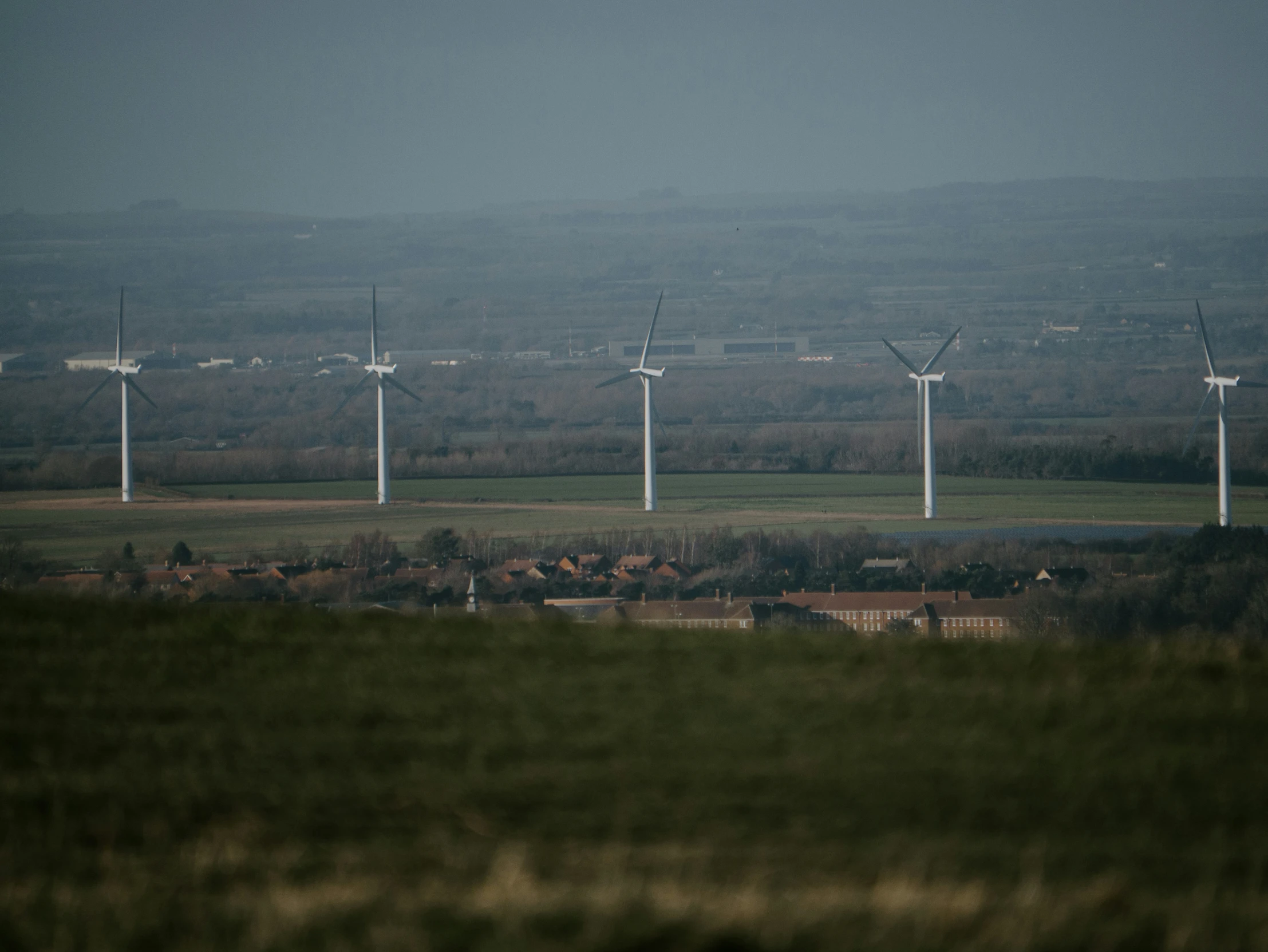 wind turbines standing on the horizon with mountains in the background