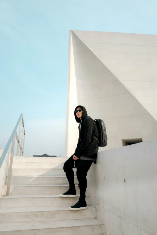 a man in a hoodie sitting on some stairs