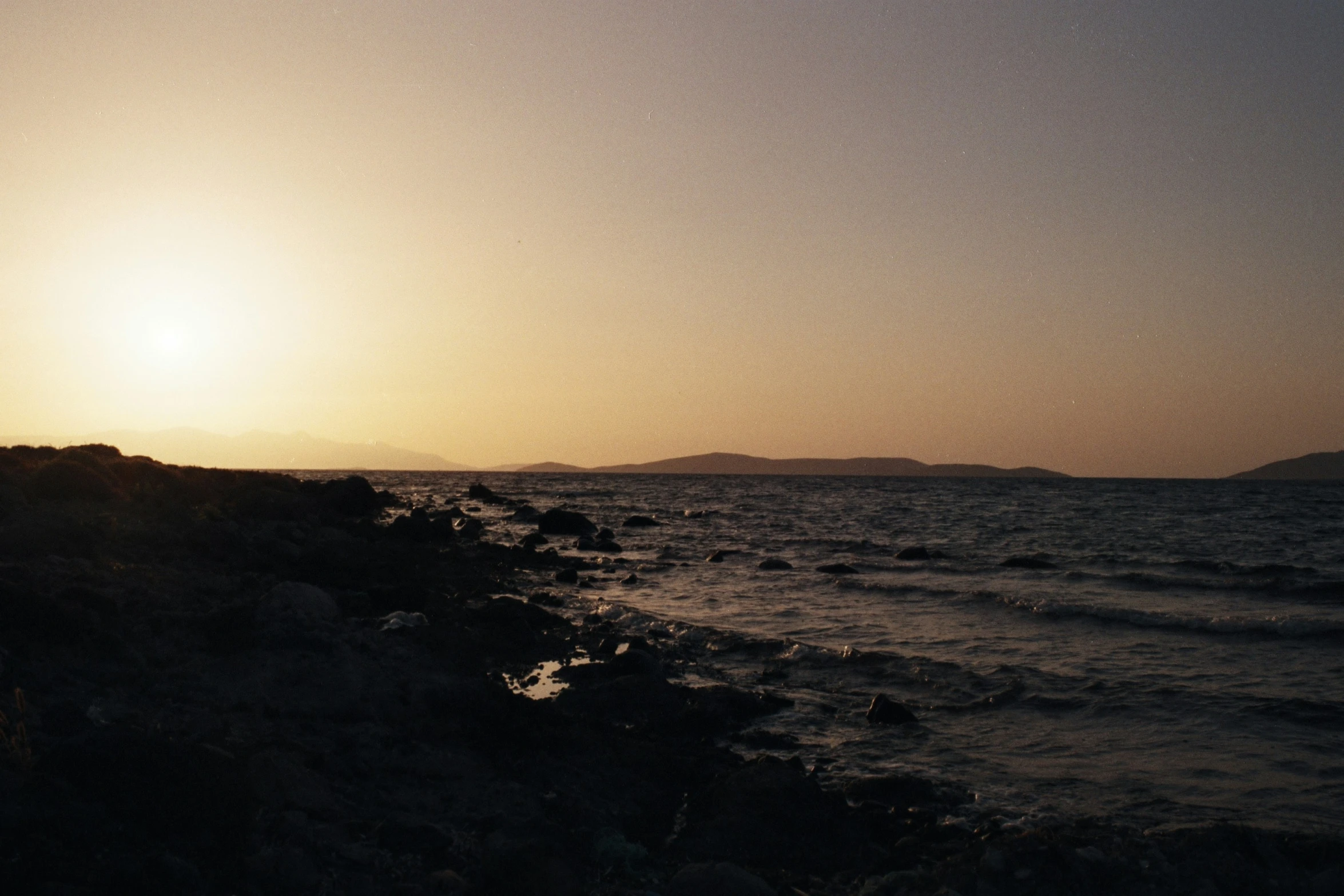 the sun sets as the ocean waves pass by