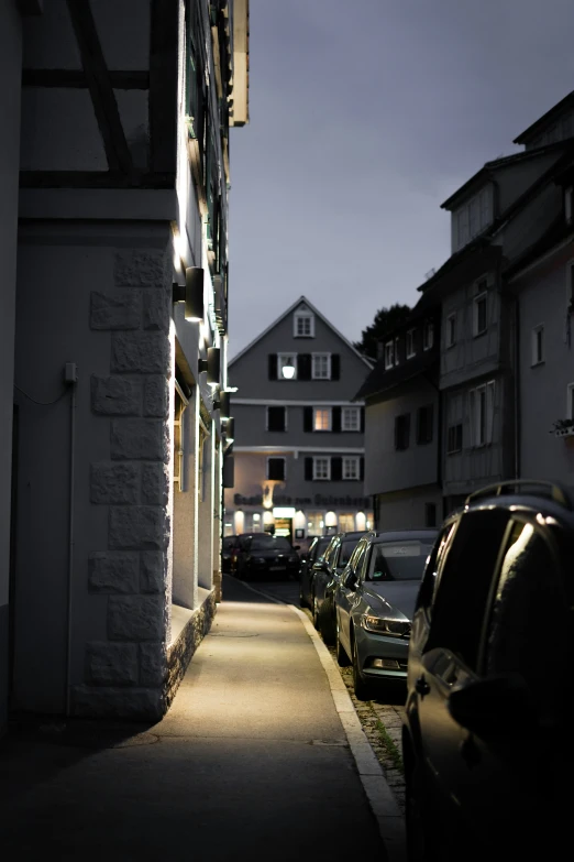 cars parked outside of a building on the side of a sidewalk