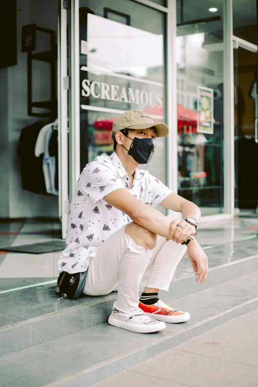 a man sits on the sidewalk in front of a clothing store