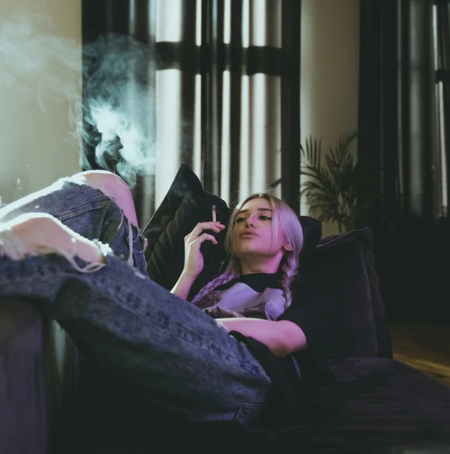 a woman in jeans smoking and sitting on a couch