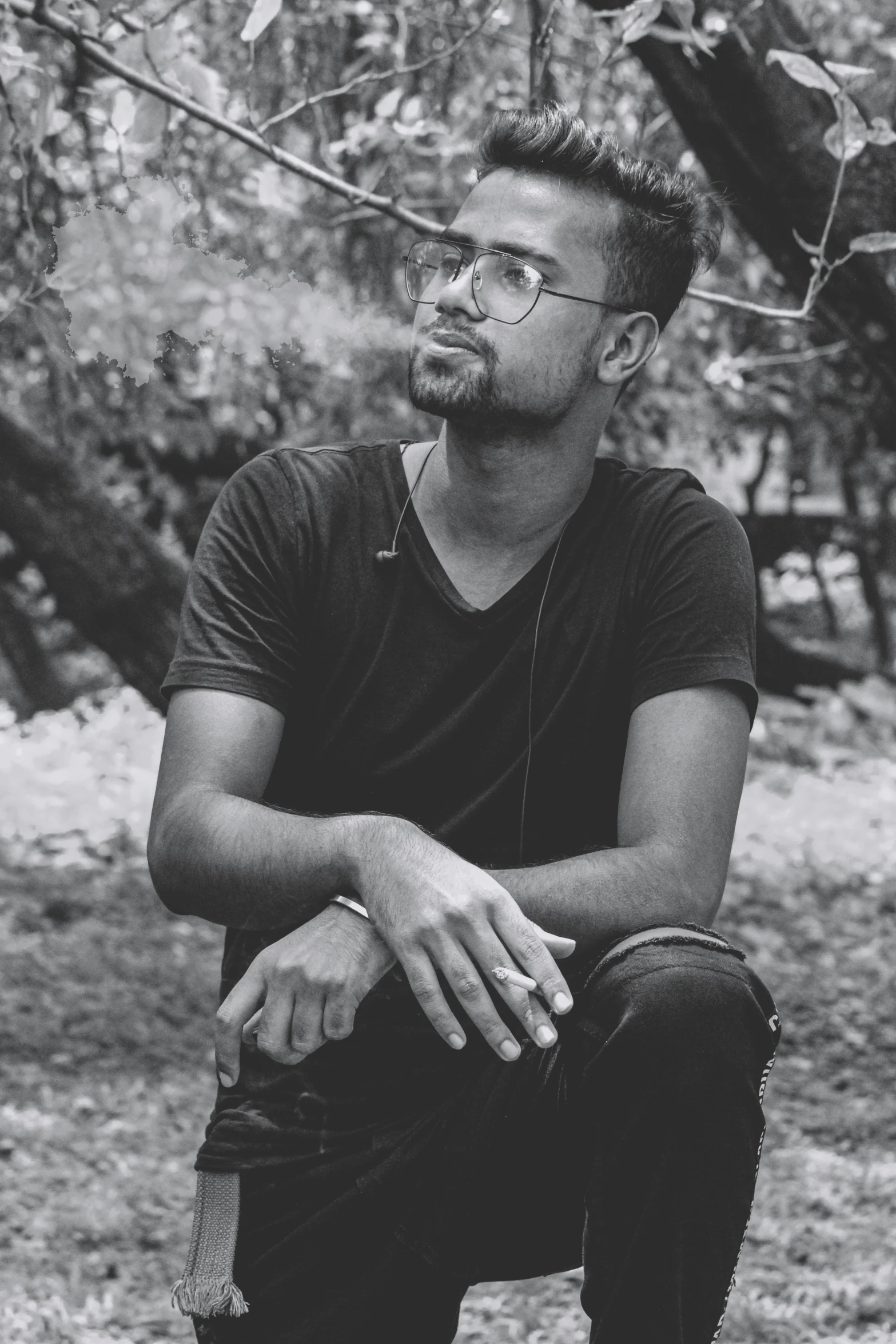 a young man wearing glasses, a black shirt and a silver ring