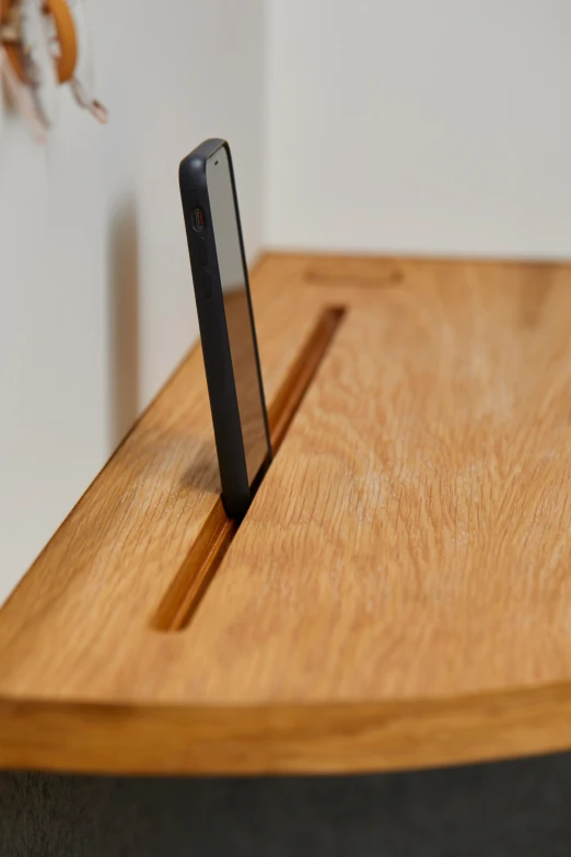 an iphone sits on a stand that is on a wood table