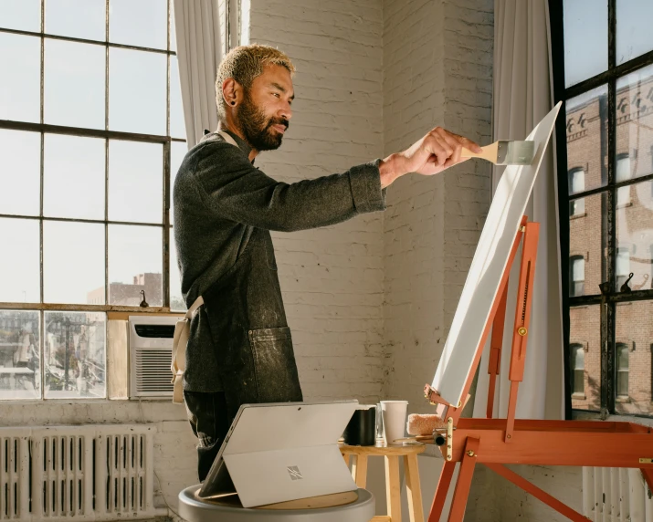 man in an office setting holds out a piece of art