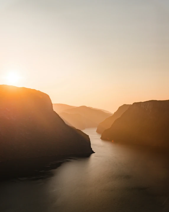 the sun sets over the mountains and water