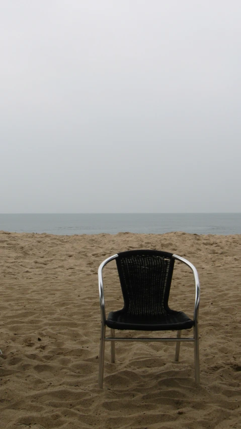 an empty chair is on the beach with the ocean in the background