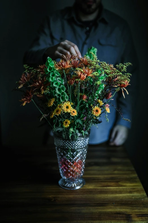 man arranging flowers in an empty vase on table