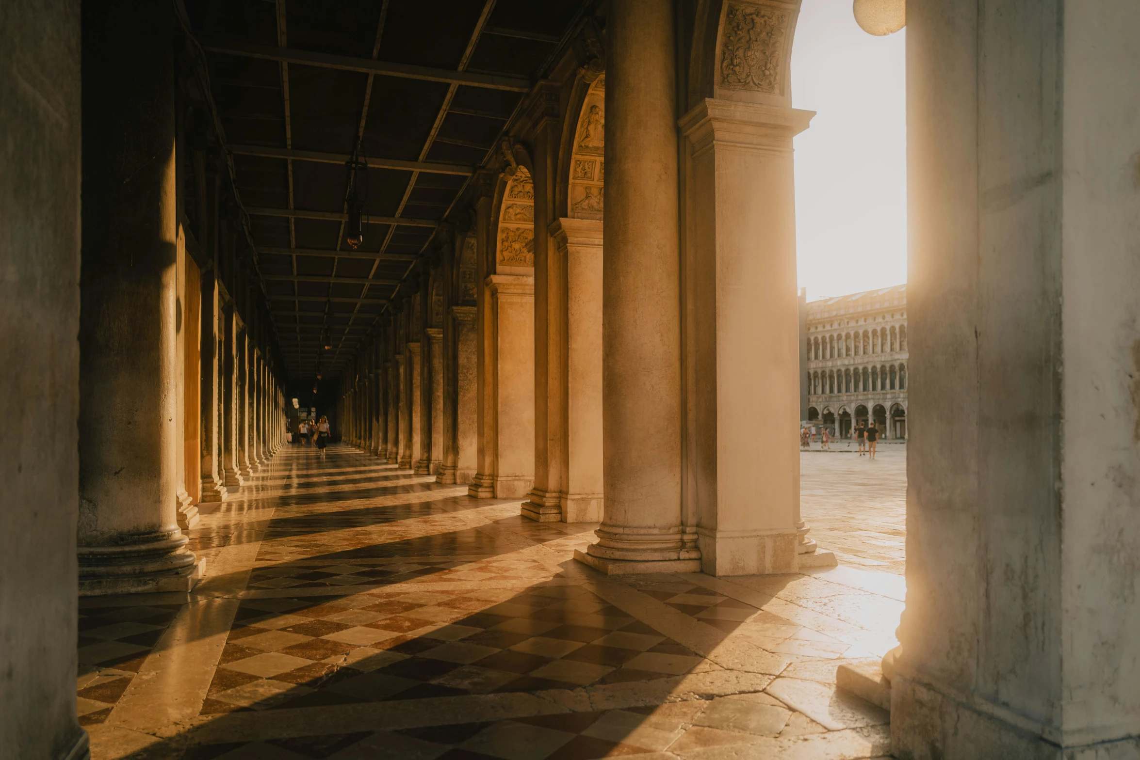 a corridor with columns and a tiled floor in an old building