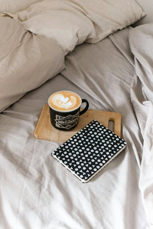 there is a cup of coffee and some papers on the bed