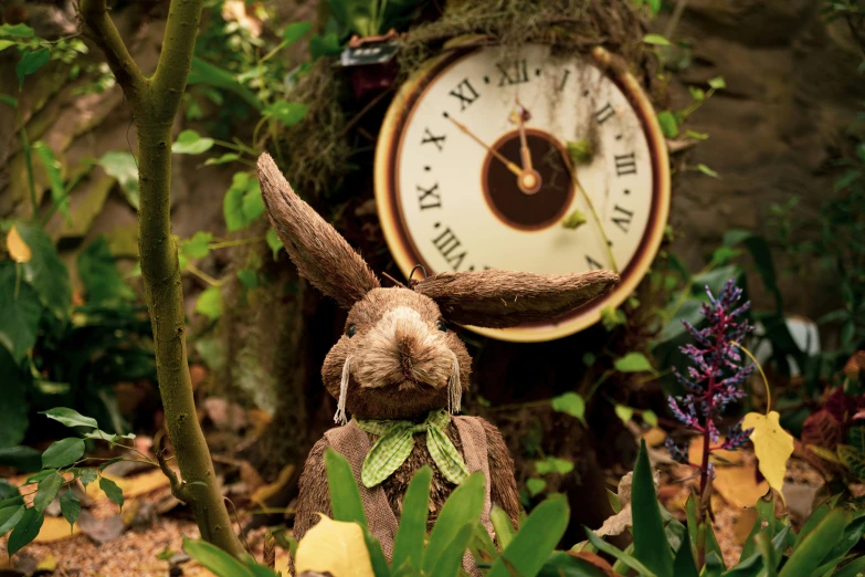 an outdoor rabbit sits in the leaves beside a clock