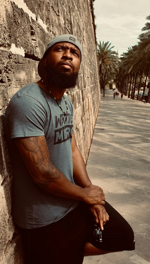 a man leaning against the side of a brick wall