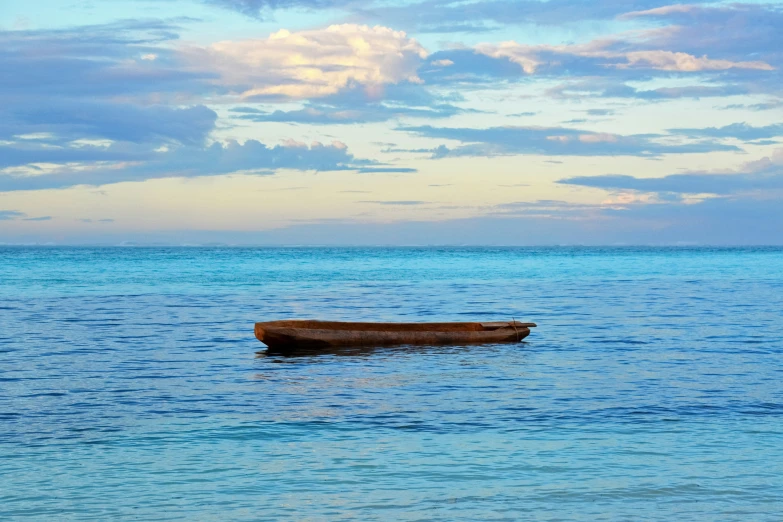 a boat on the water next to shore with clouds