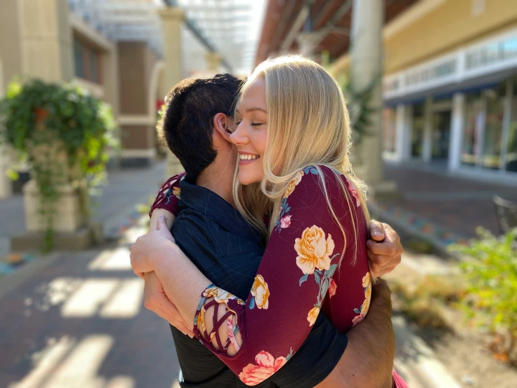 two people hugging each other while walking down the street