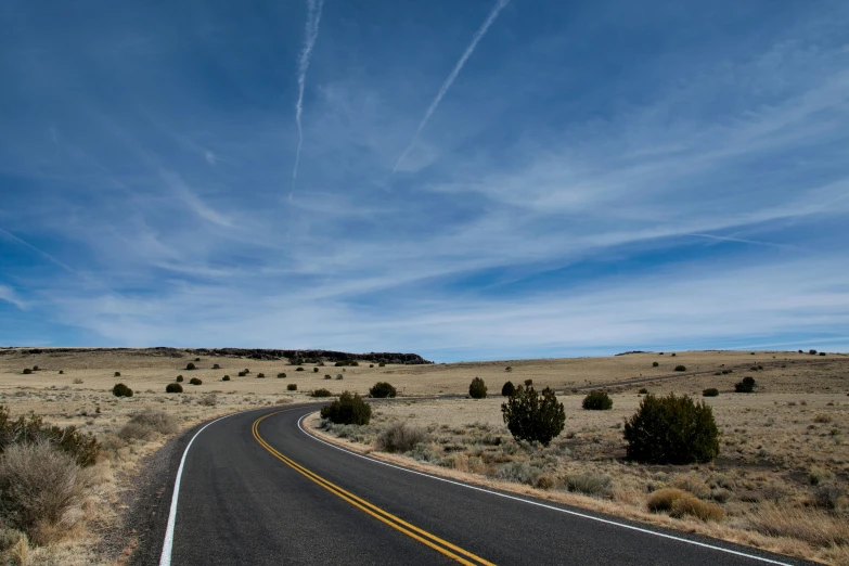 an empty road on the edge of a plain with a sign that says stop