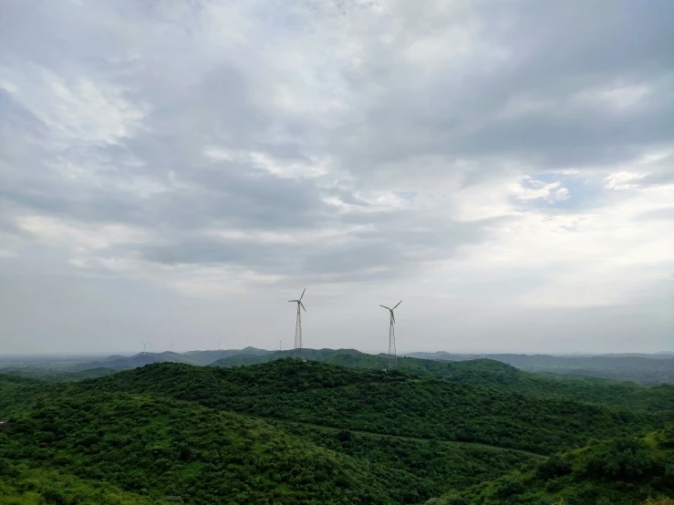 three wind turbines on a green hill side