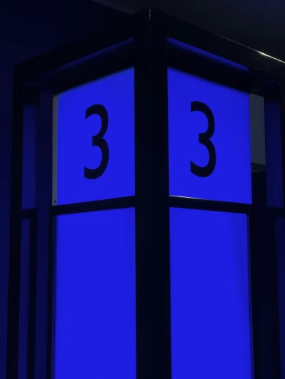 an illuminated clock in a building with three on it's sides