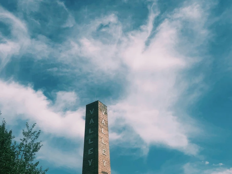 an old brick clock tower against a cloudy blue sky