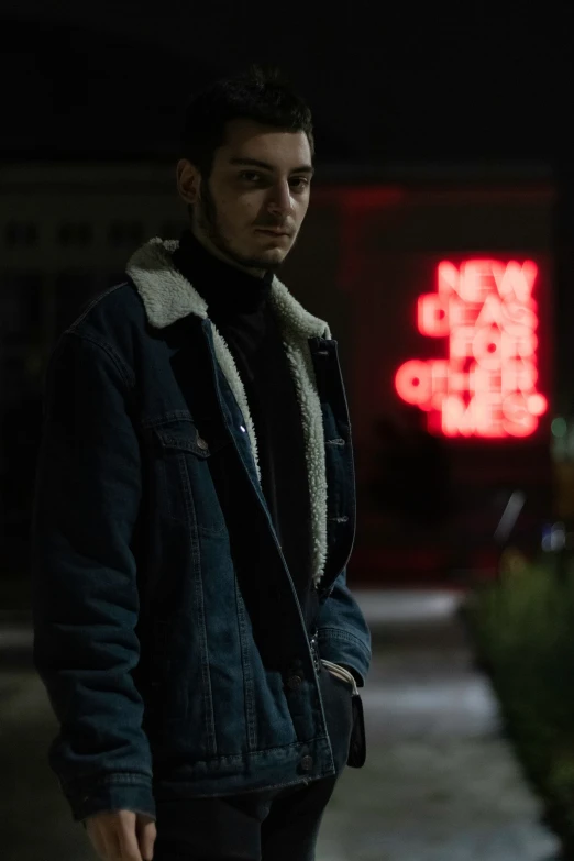 man in a coat stands in a dark street at night