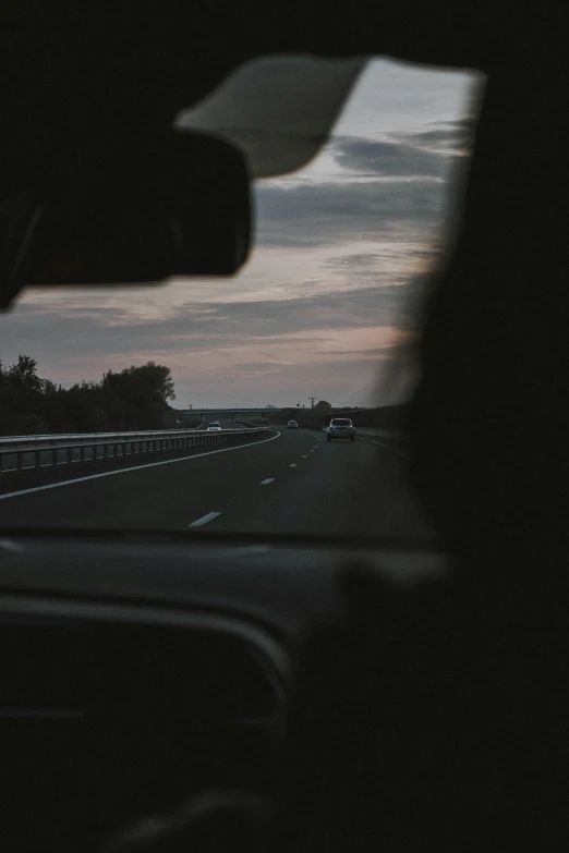 a road from a car's dashboard at dusk